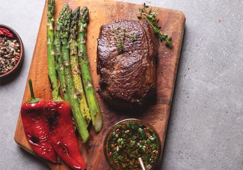 venison, asparagus and peppers arranged atop a wooden board