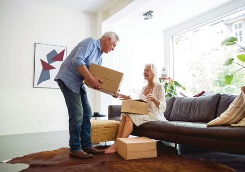 senior couple packing up their belongings into cardboard boxes