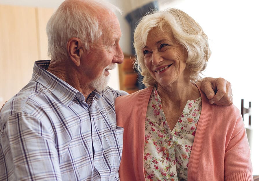 senior couple hugging while sitting on sofa at home