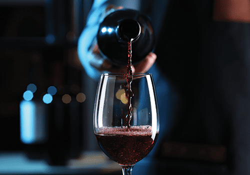 close up of someone pouring a glass of red wine