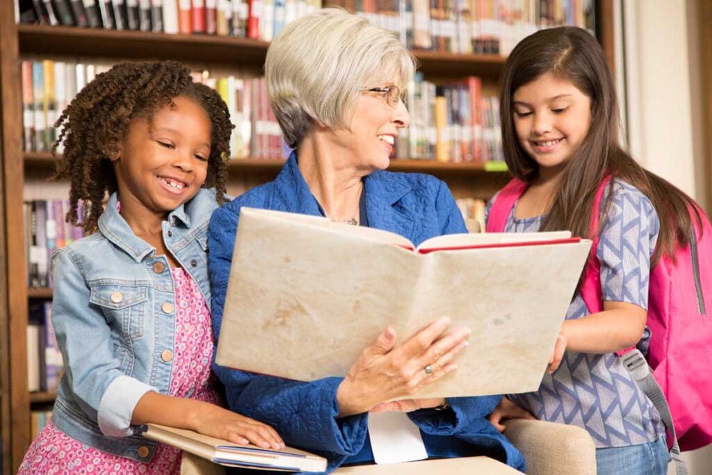 a senior woman reading a book to elementary school children