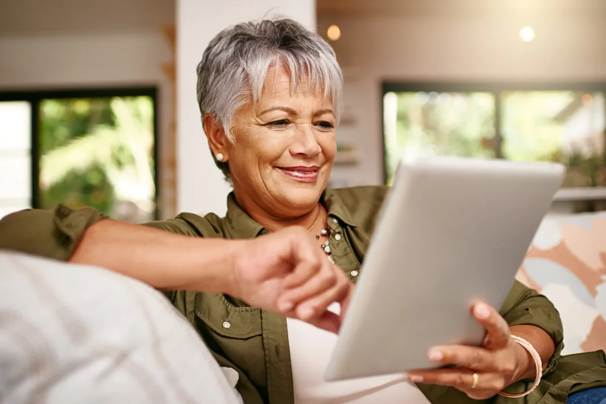 a senior woman sitting on the couch using her tablet